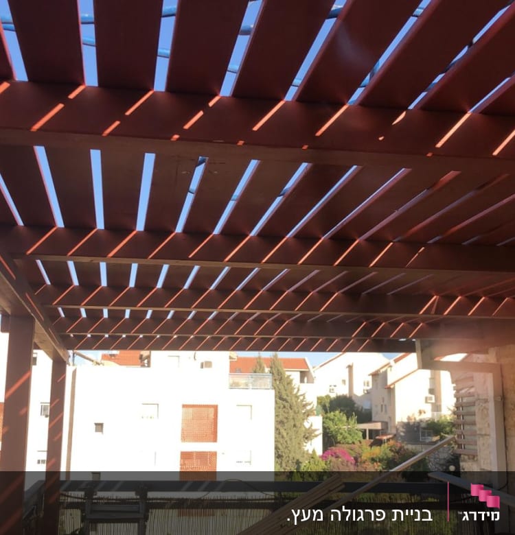 פרגולה מעץ עם קורות אופקיות בגינה